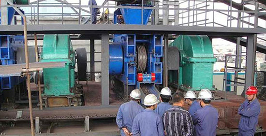 a hydraulic roller briquette press machine is briquetting mineral powder with workers around